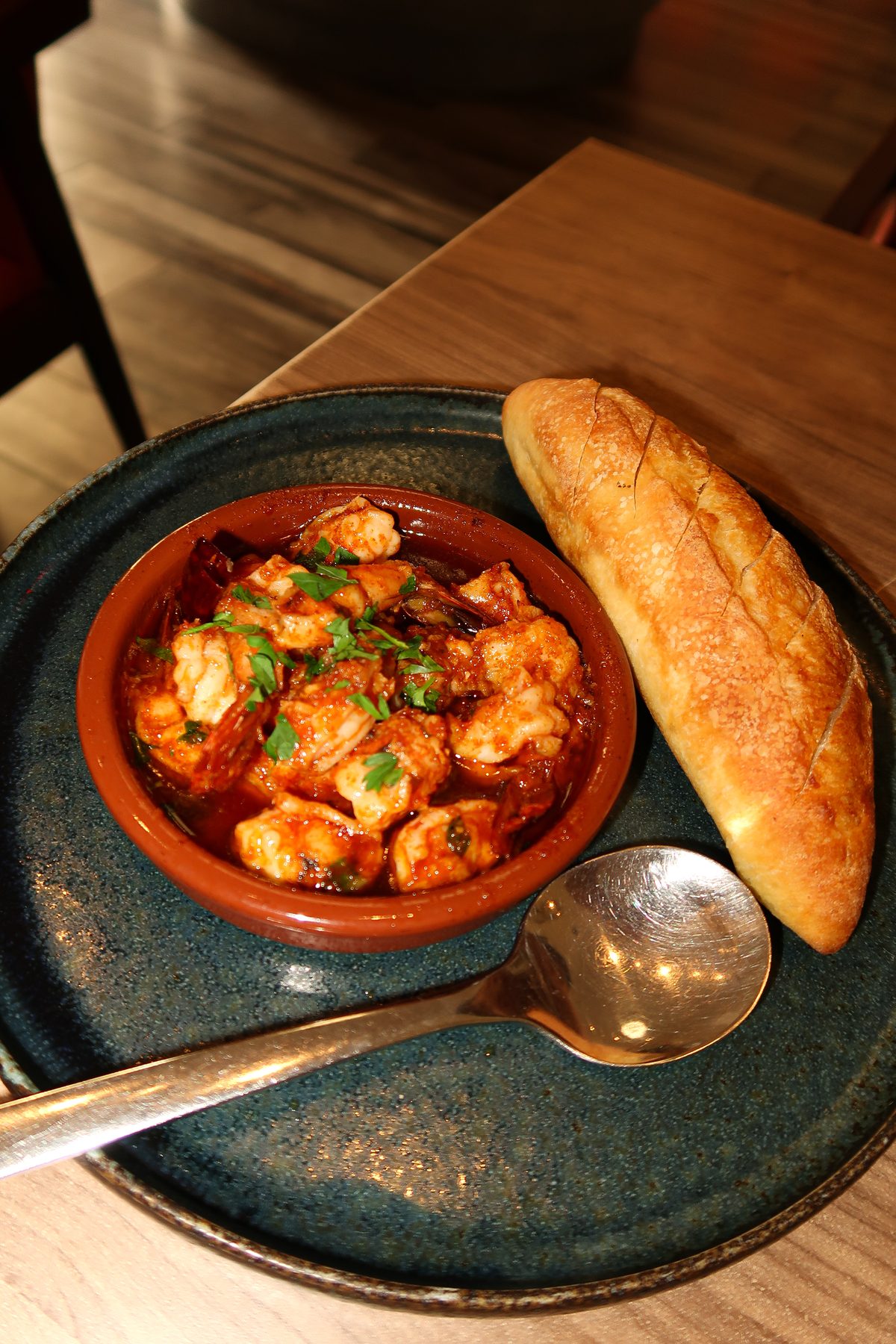 Shrimp Ajillo sizzling in garlic oil with warm homemade baguette