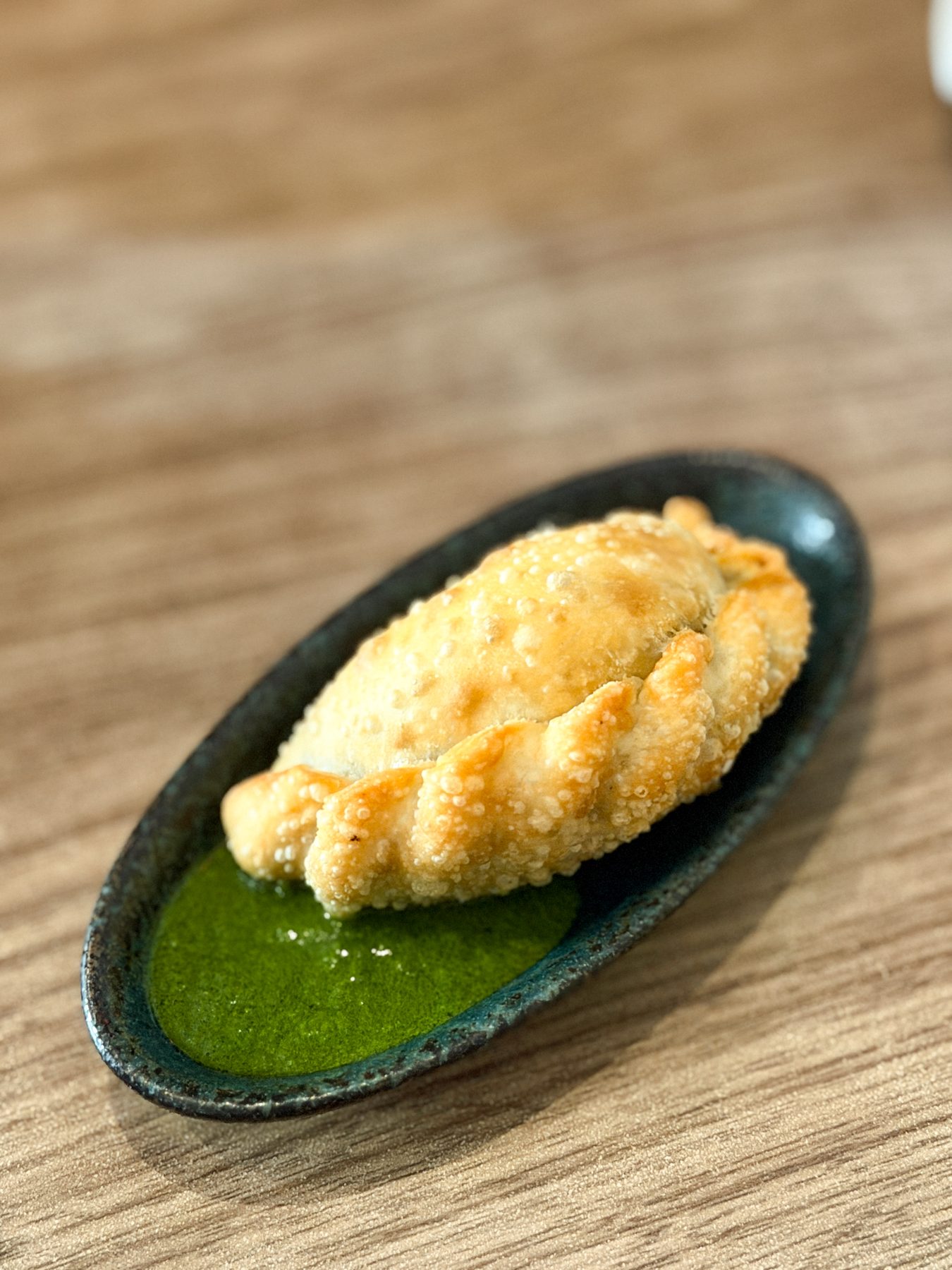 Golden empanada with vibrant chimichurri sauce